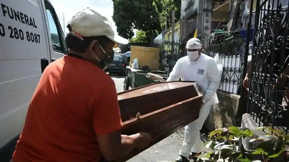 A relative and a worker of the Funeral SOS of the city of Manaus, wearing protective clothing, remove the coffin of Amadeu Garcia da Silva, 80, from his house amid the coronavirus disease outbreak, in Manaus, Brazil.