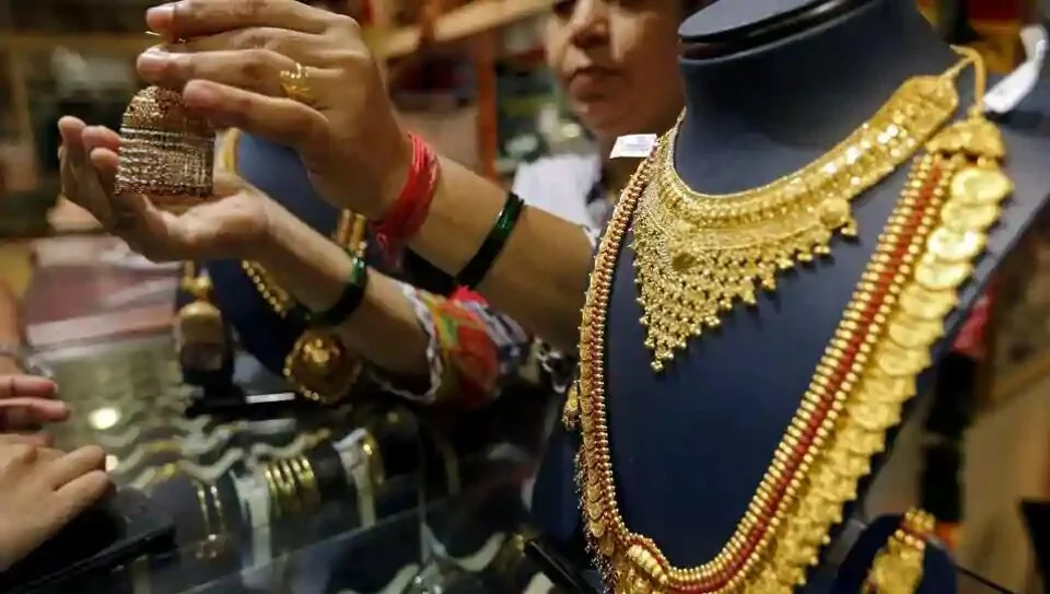 A saleswoman shows a gold earring to customers at a jewellery showroom in Mumbai, India.