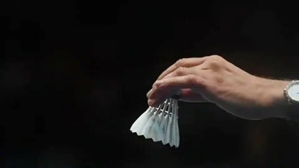 A match official places a new shuttlecock on a racket