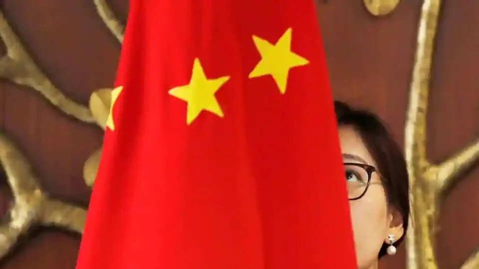 A Chinese official adjusts a Chinese flag before the start of a meeting in New Delhi, India.