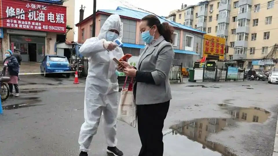 A worker in protective suit takes body temperature measurement of a woman following the coronavirus disease outbreak in Jilin, Jilin province, China.