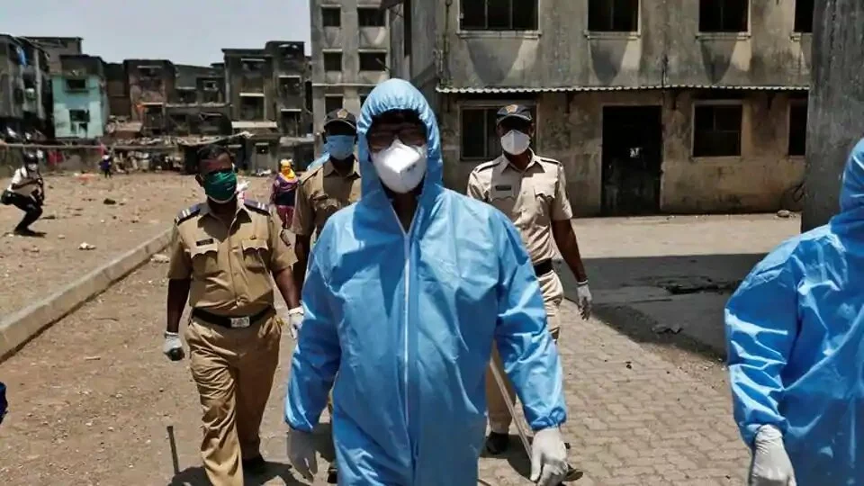 Health workers wearing hazmat suits and masks are accompanied by police officers as they conduct an inspection in a residential area, during a nationwide lockdown in India to slow the spread of Covid-19, in Dharavi, one of Asia