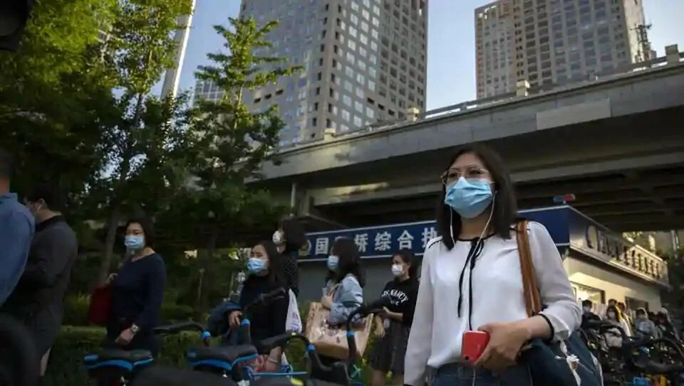 Commuters wearing face masks to protect against the new coronavirus walk through the central business district in Beijing, Tuesday, May 19, 2020. China reported six new cases Tuesday, a day after Chinese President Xi Jinping announced his country would provide $2 billion to help respond to the outbreak and its economic fallout. (AP Photo/Mark Schiefelbein)