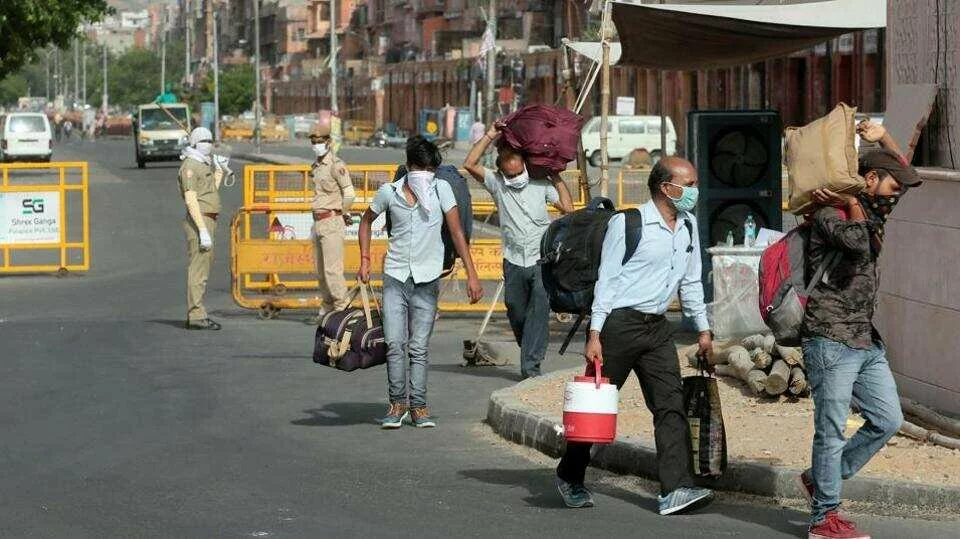 People carrying luggage pass barricades placed at the Ramganj coronavirus hotspot in Jaipur, Rajasthan on Monday.