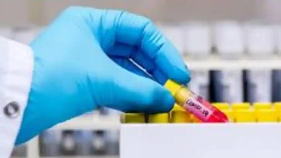 A laboratory worker removes a test tube containing a patient