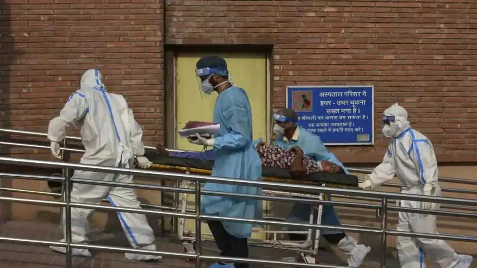 Medical professionals wearing PPE coveralls escort a patient suspected of coronavirus infection into the the Covid-19 ward at LNJP Hospital in New Delhi.