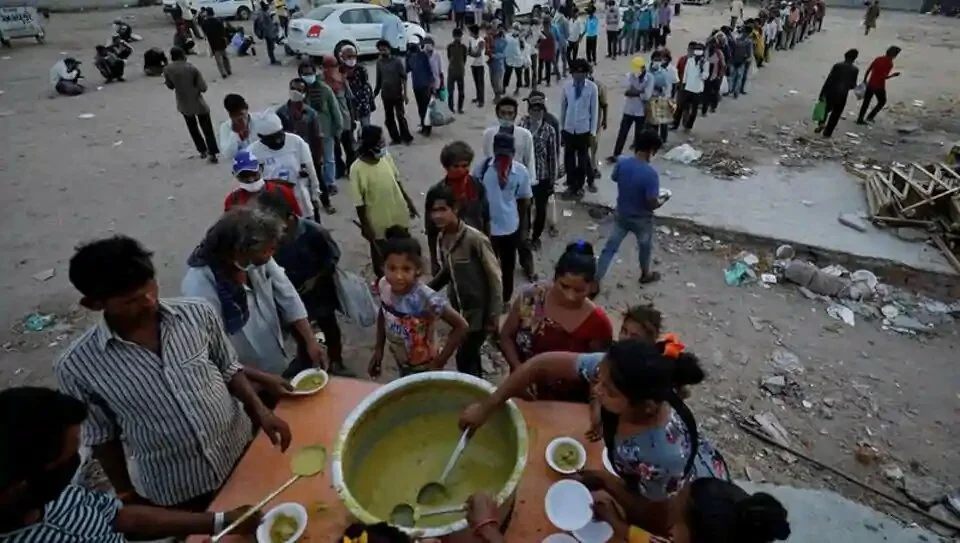 FILE PHOTO: Migrant workers and homeless people queue to receive free food during a nationwide lockdown to slow the spread of the coronavirus disease (COVID-19), in Ahmedabad, India, May 1, 2020.