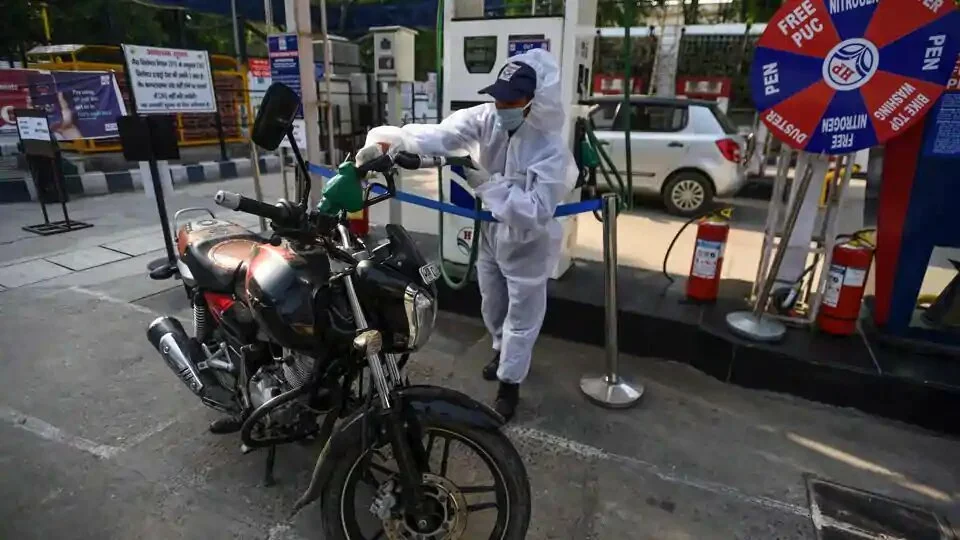 A petrol pump employee operates wearing PPE overalls.