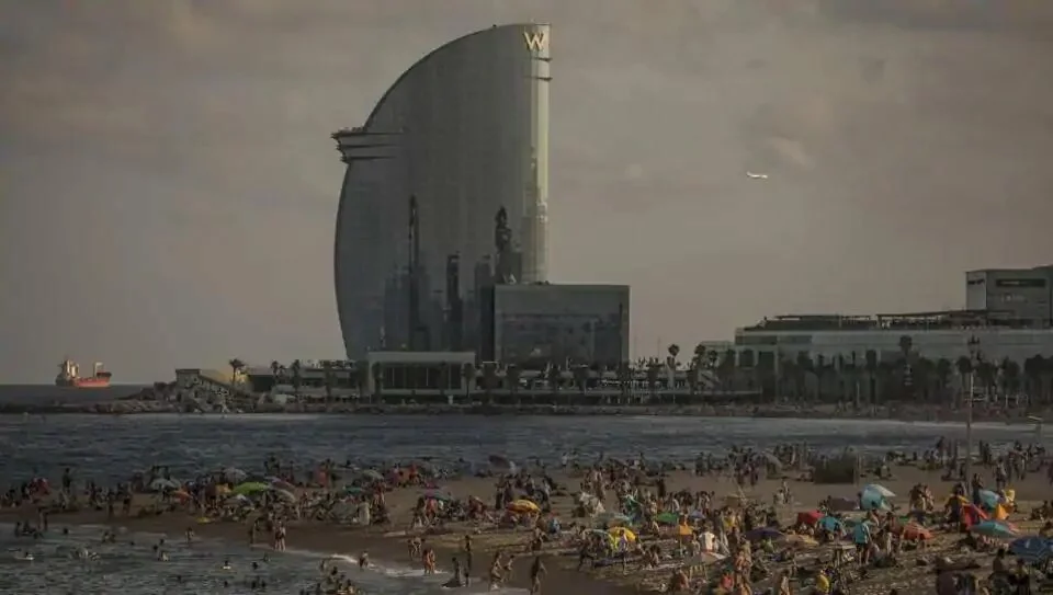 Beachgoers relax on Barceloneta beach during sunset as the The W Hotel, operated by Marriott International Inc., stands beyond in Barcelona, on Sunday, Aug. 2, 2020. Spain’s economy suffered a bigger blow than expected in the second quarter, leaving it with a long recovery that’s become even tougher after a new hit to its vital tourism industry.