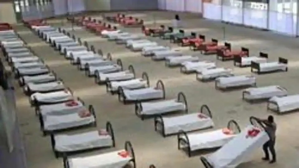 A worker arranges beds at a quarantine centre in an indoor international fair complex in Agartala.