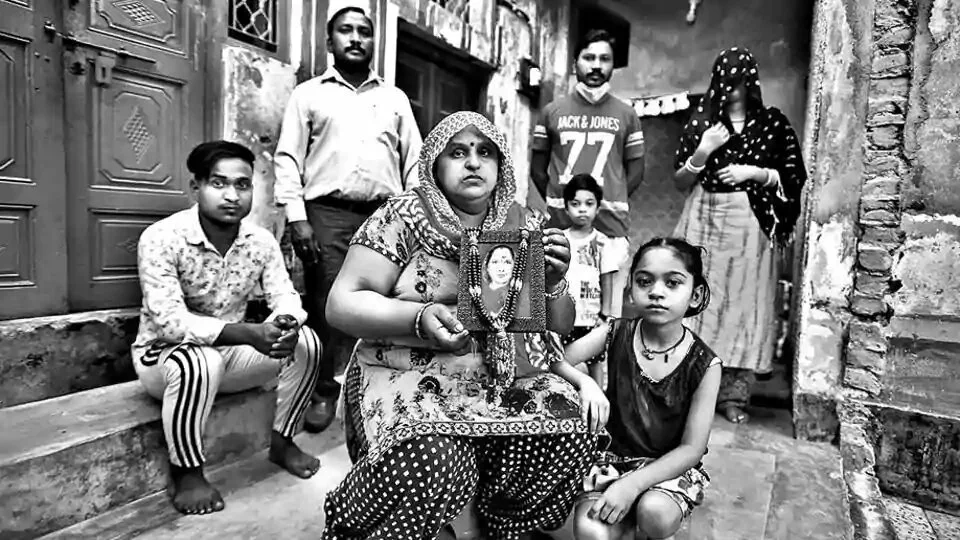 (From left) Family members Kanishk, Joginder, Arjun, Bunny, Varsha, and Megha flank Reena, who holds up a photograph of Tarawati in their Delhi home.